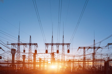 distribution electric substation with power lines and transformers, at sunset.