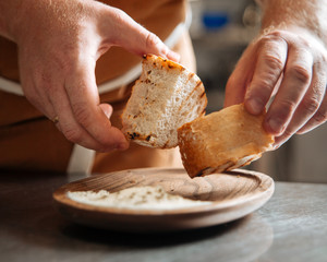 Roasted pieces of bread in man's hands over the wooden plate