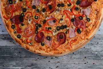 Flat lay photograph of tasty italian pizza on rustic wood. Pepperoni, cheese and peppers. Delicious food.