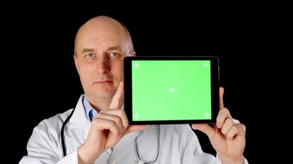 Front view of doctor holding tablet with chromakey green screen. Male medical worker wearing white overall showing modern device. Technology concept