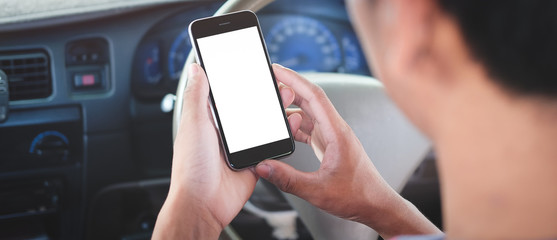 Cropped shot view The driver uses the phone while driving. Modern smart phone with round edges. Isolated screen for mockup. Car navigation display in background.