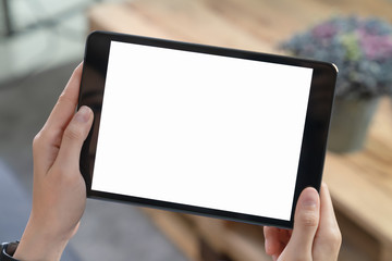 Close-up of hand holding black tablet on sofa in living room.