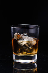a glass of whiskey with ice on a dark gradient background
