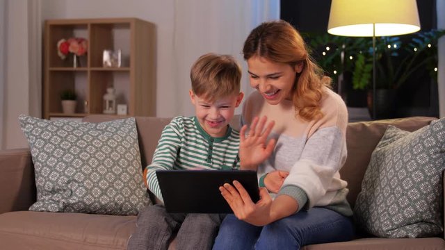 family, technology and people concept - happy mother and little son with tablet pc computer having video call at home