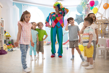 happy kids and clown on birthday party indoors