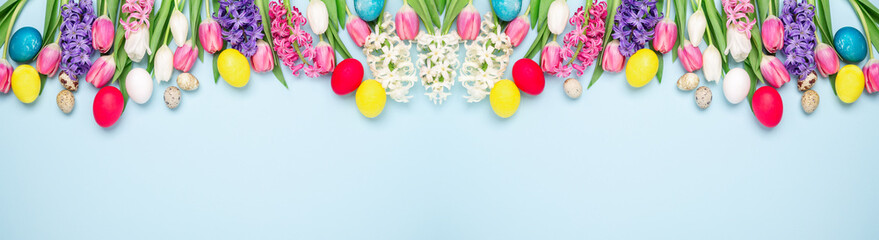 Obraz na płótnie Canvas Long horizontal banner with easter eggs, hyacinths and tulips on blue background. Easter concept. Copy space