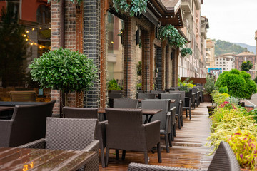 Empty terrace with tables and chairs in wood and metal at coffee and resteurant beside sidewalk in center city. Background business dramatic scene concept. Stay home concept