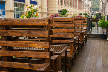 Empty terrace with tables and chairs in wood and metal at coffee and resteurant beside sidewalk in center city. Background business dramatic scene concept. Stay home concept