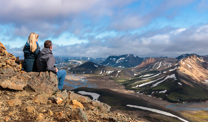 Two hikers resting atop landmannalaugar area in iceland