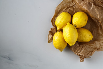lemons on parchment lie on a light marble table