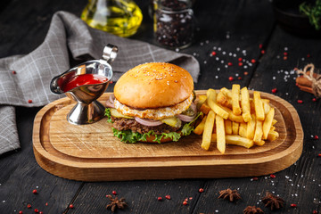 Burger set with fries and red sauce on the wooden board
