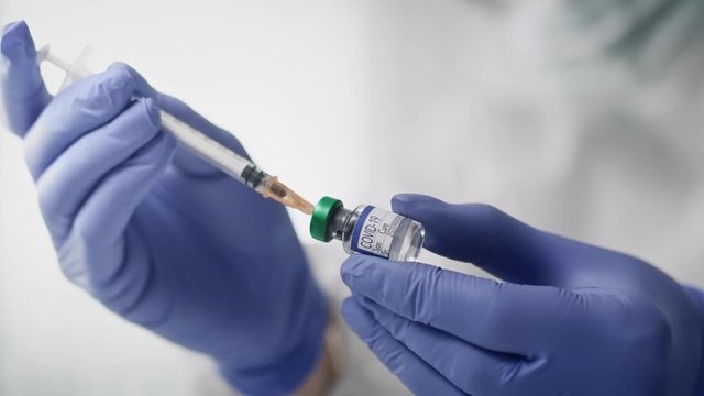 Video of doctor applying coronavirus vaccine into the syringe. Shot with RED helium camera in 8K.