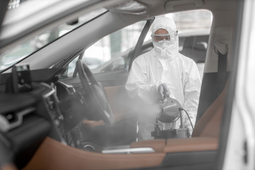 Disinfectant worker character in protective mask and suit sprays bacterial or virus in a car.