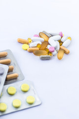 Close- up of tablets and capsules of different colors on a white background. Supplements, tablets help with diseases.Vitamins. Medicine, production of tablets and dietary supplements