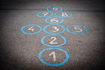 Fototapeta premium Drawings on the asphalt in the school for children's play. Hopscotch court with numbers from 1 to 8 drawn with white paint on the asphalt.Child playing hopscotch game.activities for children.School ya