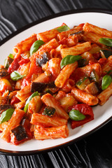 Vegetarian Tortiglioni pasta with vegetables and basil in tomato sauce close-up in a plate. vertical