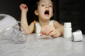 A child sits with an inhaler at home. Coronovirus treatment concept Covid19. Girl making inhalation with nebulizer at home. child asthma inhaler inhalation nebulizer steam sick cough