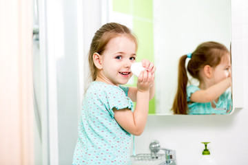 Cheerful little girl washing hands and showing soapy palms