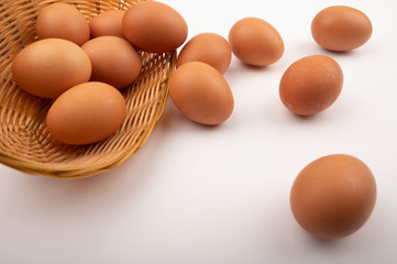 Chicken eggs in a wicker basket and eggs scattered on a white background. Close up.