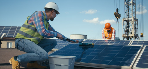 Technicians installing solar panels in sunshine