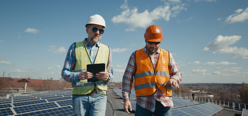 Engineer and technician discussing between solar panels
