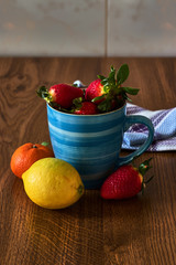 Blue mug with strawberries, a lemon and a tangerine.