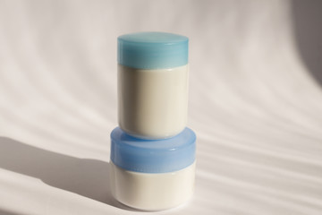 White blank mockup of bottle cream containers with blue cups. Professional tubes for facial and body treatment. Skincare and wellness concept.
