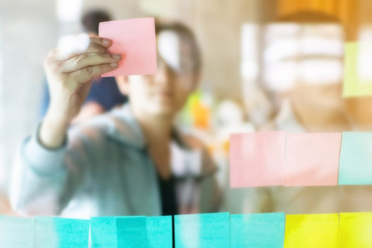 Hand And Sticky Note With Asian Business Woman Leader And  Team  Wearing Casual Outfit Meeting  With Business Partner Using Note Paper For Present Idea .Agile And Scrum Meeting