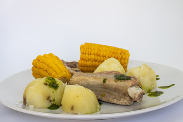 Potatoes, pineapples and ribs, a typical dish from the island of Tenerife. The potatoes, pineapples and ribs are accompanied by a green mojo. The green mojo is coriander. Tipical from canary islands.