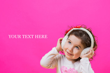 Little cheerful happy beautiful girl standing isolated on a yellow background in soft headphones, childish emotions. your text here