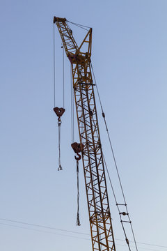 High construction crane on blue sky background. Backlit images.