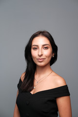 Obraz premium A large portrait of a middle-aged woman (30-35 years old) with dark hair and brown eyes in a black dress on a light background.