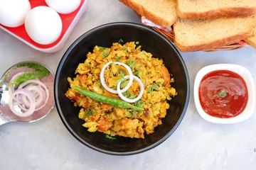 Indian Breakfast Dish - Parsi Akuri or Anda Bhurji or Indian spicy scrambled eggs served with toasted brown bread & ketchup. Famous Indian street food. Ingredients background with copy space.