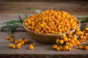 Sea buckthorn in the plate and around Sea buckthorn berries on wooden table