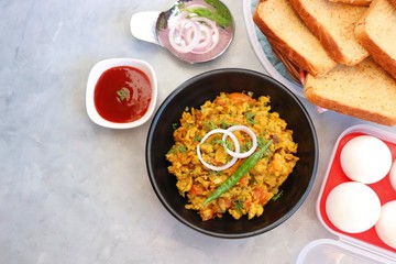 Indian Breakfast Dish - Parsi Akuri or Anda Bhurji or Indian spicy scrambled eggs served with toasted brown bread & ketchup. Famous Indian street food. Ingredients background with copy space.