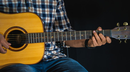 A guitarist playing a chord an acoustic guitar