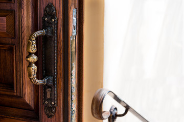 Open wooden door with antique bronze handle, railings and copy space. 