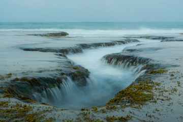 Unique ocean water flow through rocks phenomenon like a waterfall. Perfect location for photographers near Sawarna, Banten province, Java, Indonesia
