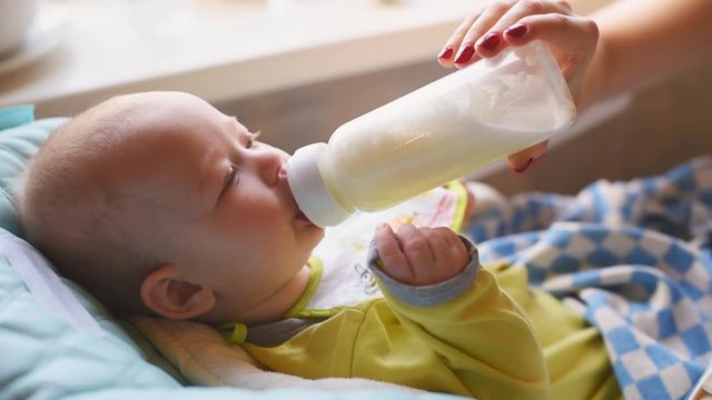 Woman feeds her baby milk from a bottle