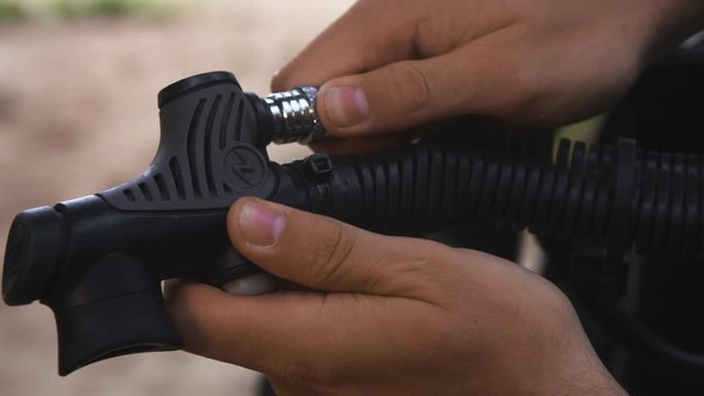 Man attaches valve into his BCD (buoyancy control device) diving equipment, close up