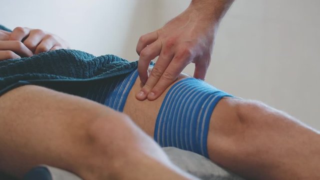 Physiotherapist palping patient muscle during a electric stimulation treatment. Slow motion close up