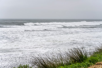 Tasman sea waves and froth on sand shore at Woodpecker bay, near Tiromoana, West Coast, New Zealand