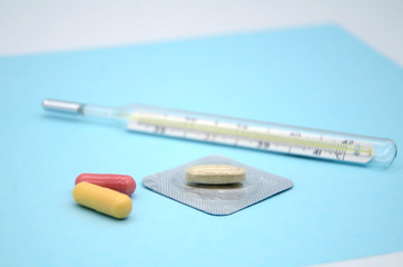 Mercury thermometer, ampoules, capsules on a blue background. the concept virus Covid-19....