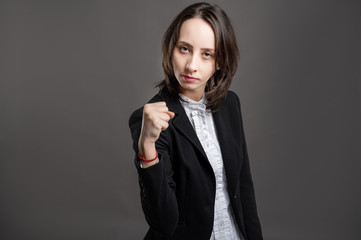 Obraz premium Portrait of wonderful young business woman showing fist, poseing on isolated gray background