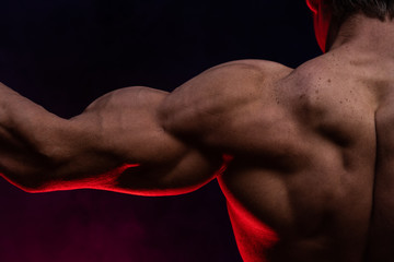 Muscular man showing muscles isolated on the black background close up. Concept of healthy...