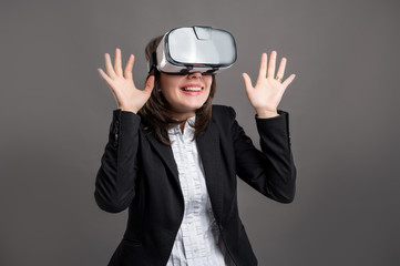 Portrait of wonderful young business woman wearing virtual reality VR glasses, poseing on isolated gray background