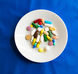 white plate with pills on blue background