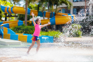 Child playing under tip bucket in water park.