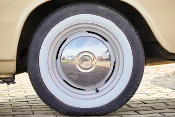 Retro wheel of the classic car in the old style. Oldtimer. White painted tire stylized as an old tire. A car from the 50s.