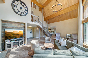 Amazing living room with three story tall vaulted wooden ceiling, huge windows, two large round chandeliers, venetian plaster, open staircase, beautiful design.
